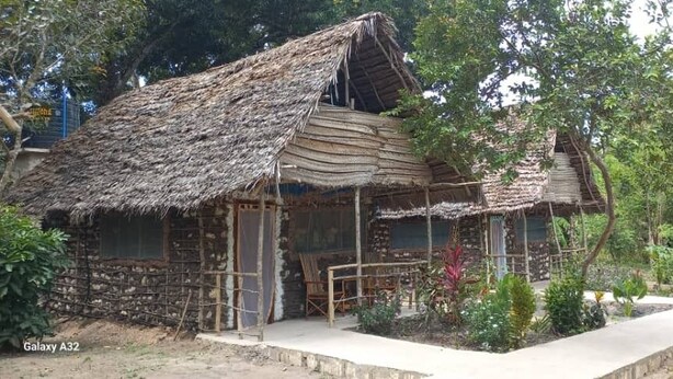 Una casa tradicional con techo de paja, un porche de madera y un pequeño jardín.