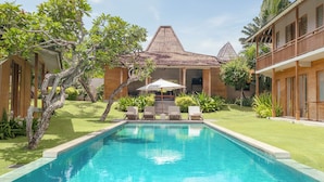 A pool with lounge chairs, a building with a tiled roof, and a well-maintained garden. - Alea Estate by Villa Finder (Kerobokan)