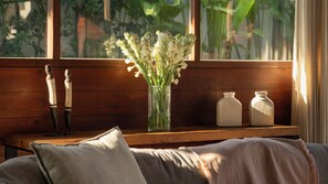 A wooden bench with a vase of flowers, two bottles, and a decorative item. - Alea Estate by Villa Finder (Kerobokan)