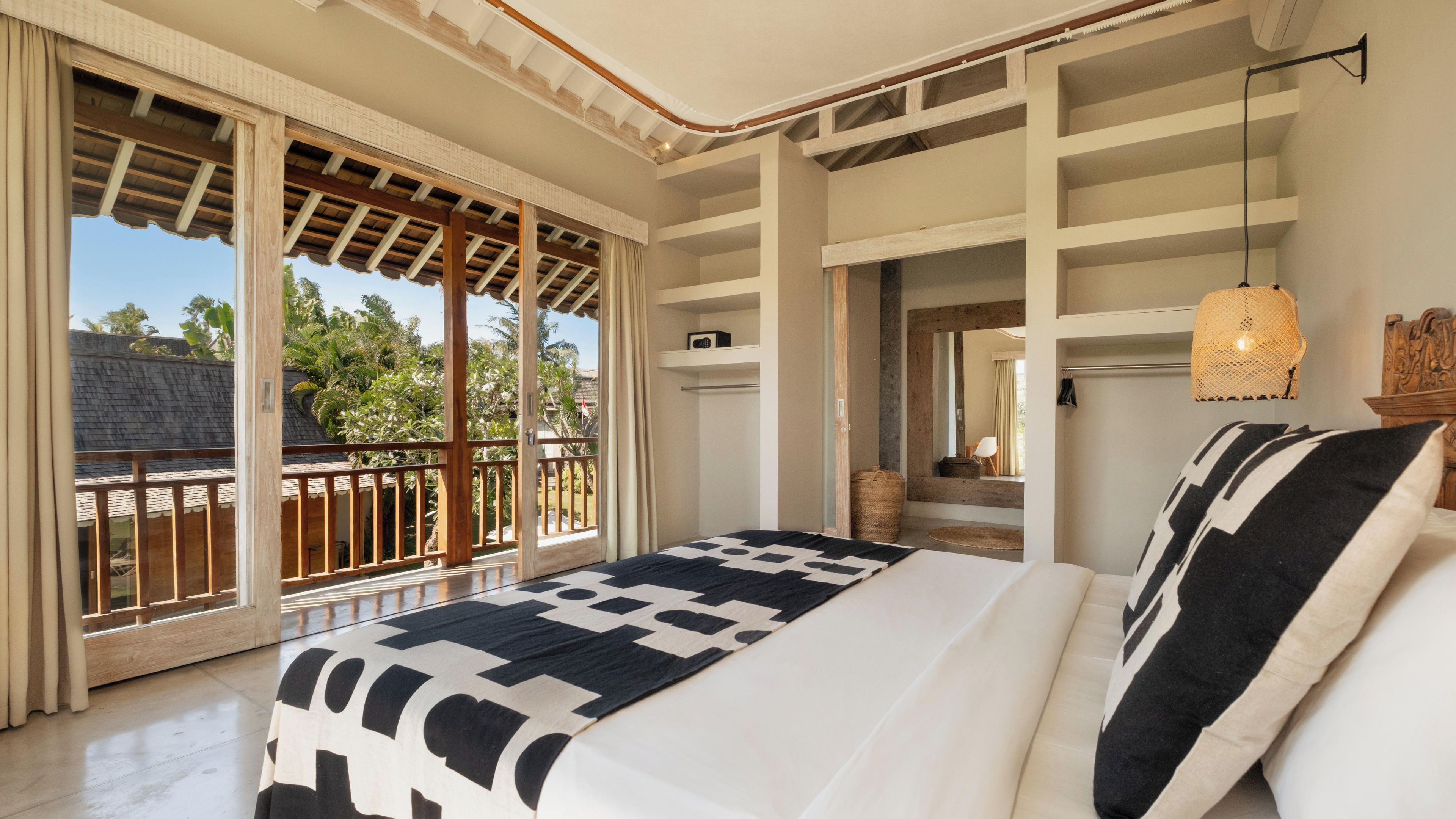 A bedroom with a large bed, a view of the outdoors, and a balcony.