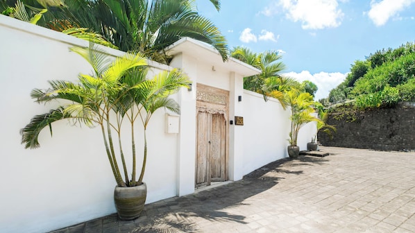 Un bâtiment blanc avec une porte en bois, des plantes en pot et un mur en pierre.