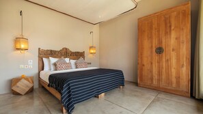 A bedroom with a bed, bedside lamps, a wooden wardrobe, and a nightstand. - Alea Estate by Villa Finder (Kerobokan)