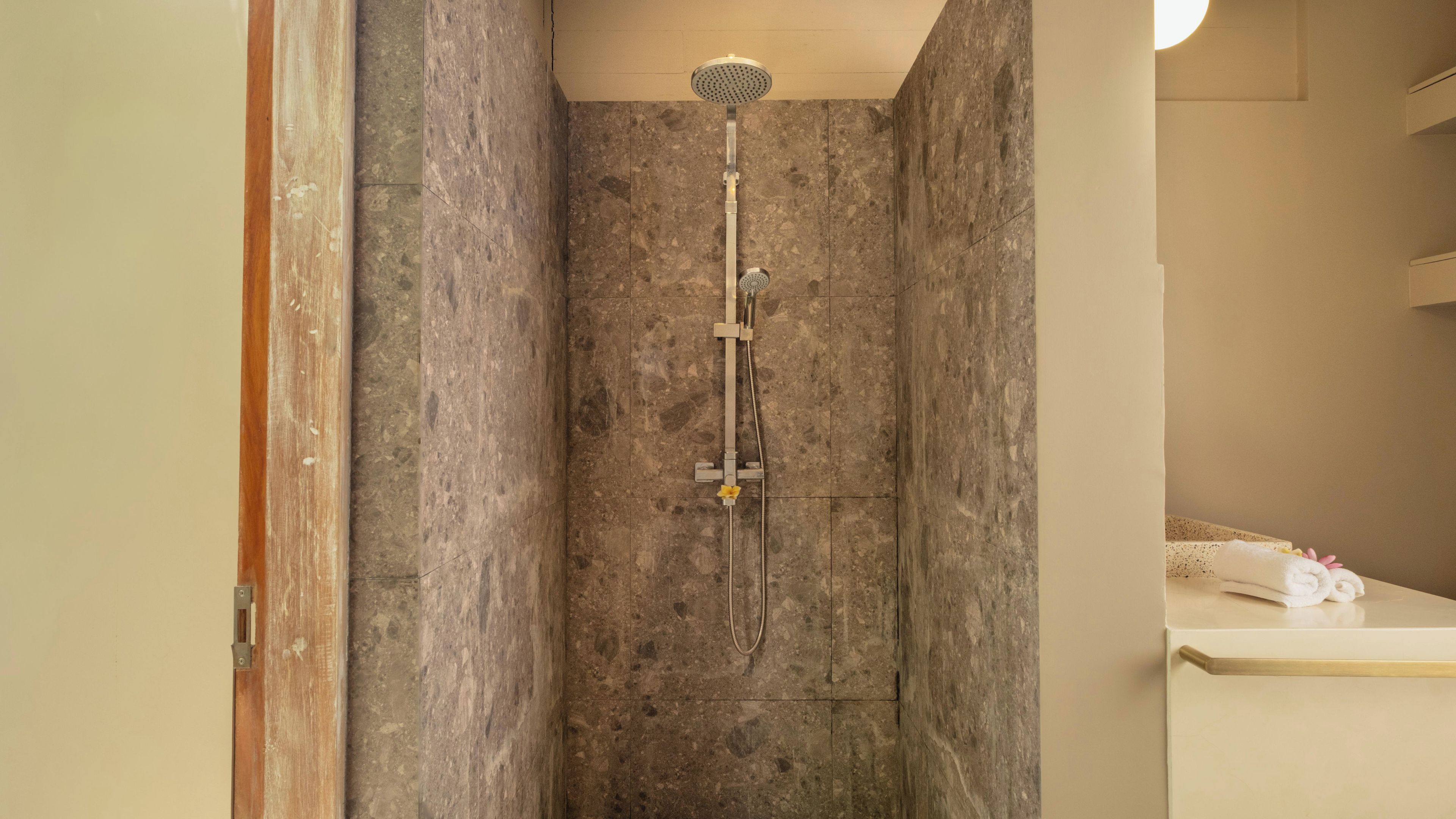 A shower with a handheld showerhead, a handheld shower attachment, and a wall-mounted control panel.