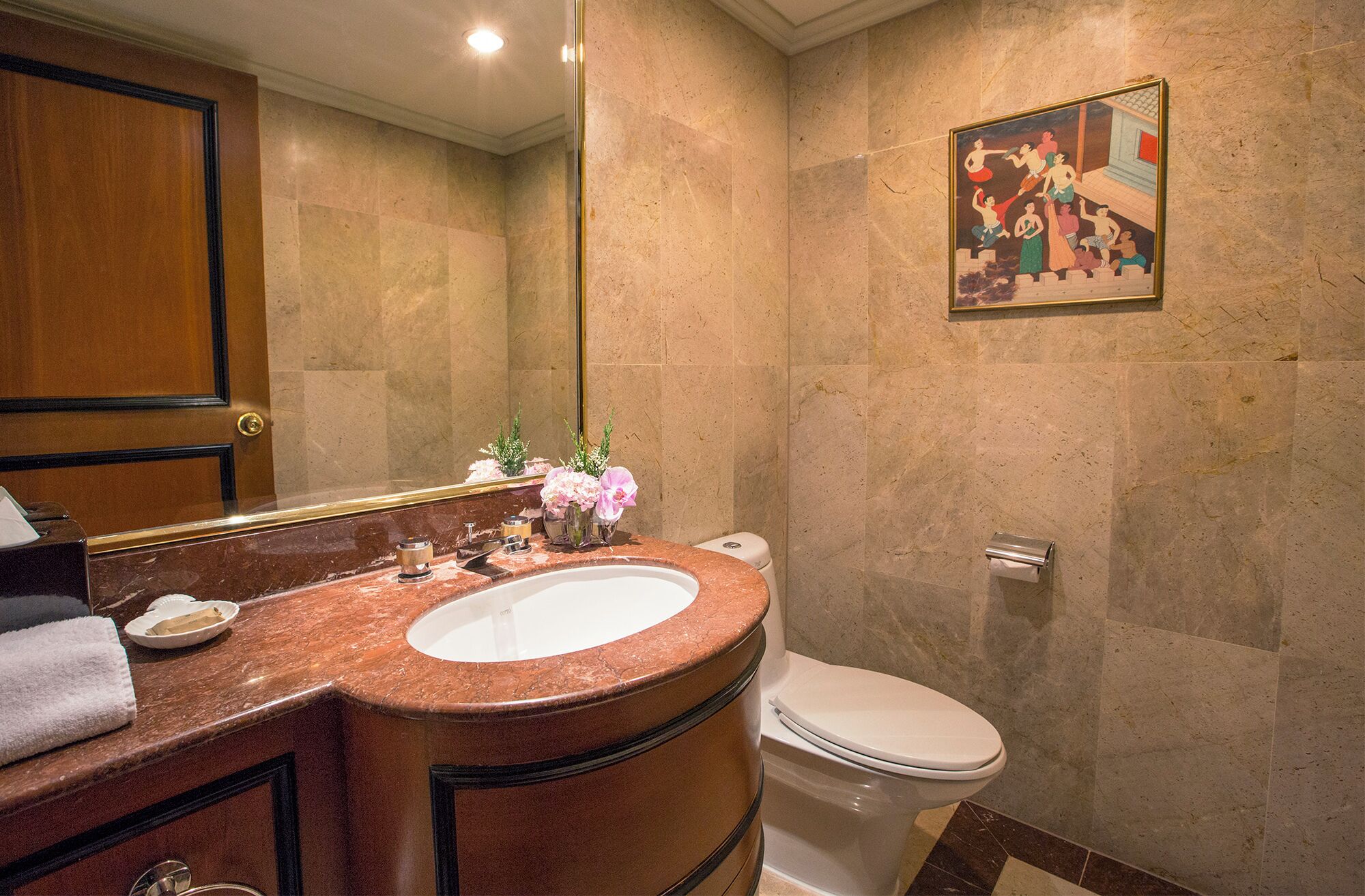 A bathroom with a marble sink, a toilet, and a large mirror.