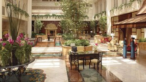 A spacious atrium with a high ceiling, marble flooring, and a central water feature.