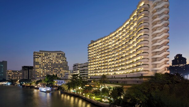A high-rise hotel with multiple balconies, a waterfront view, and a modern architectural design.