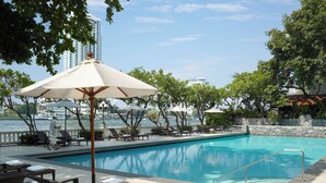 A poolside area with lounge chairs, umbrellas, and a view of the water and buildings.