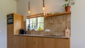 A kitchen with wooden cabinets, a built-in oven, a window with a view, and a countertop with various items.