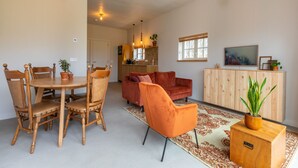 A spacious living area with a dining table, chairs, a sofa, and a cabinet.