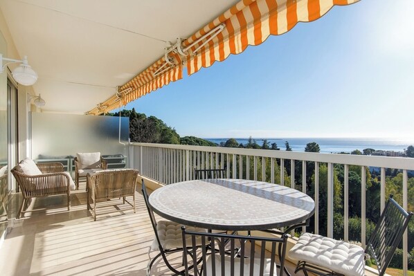 A balcony with a round table and wicker chairs, overlooking a scenic view. - Upstays Sea View Terrace 83m² Apartment (Cannes)