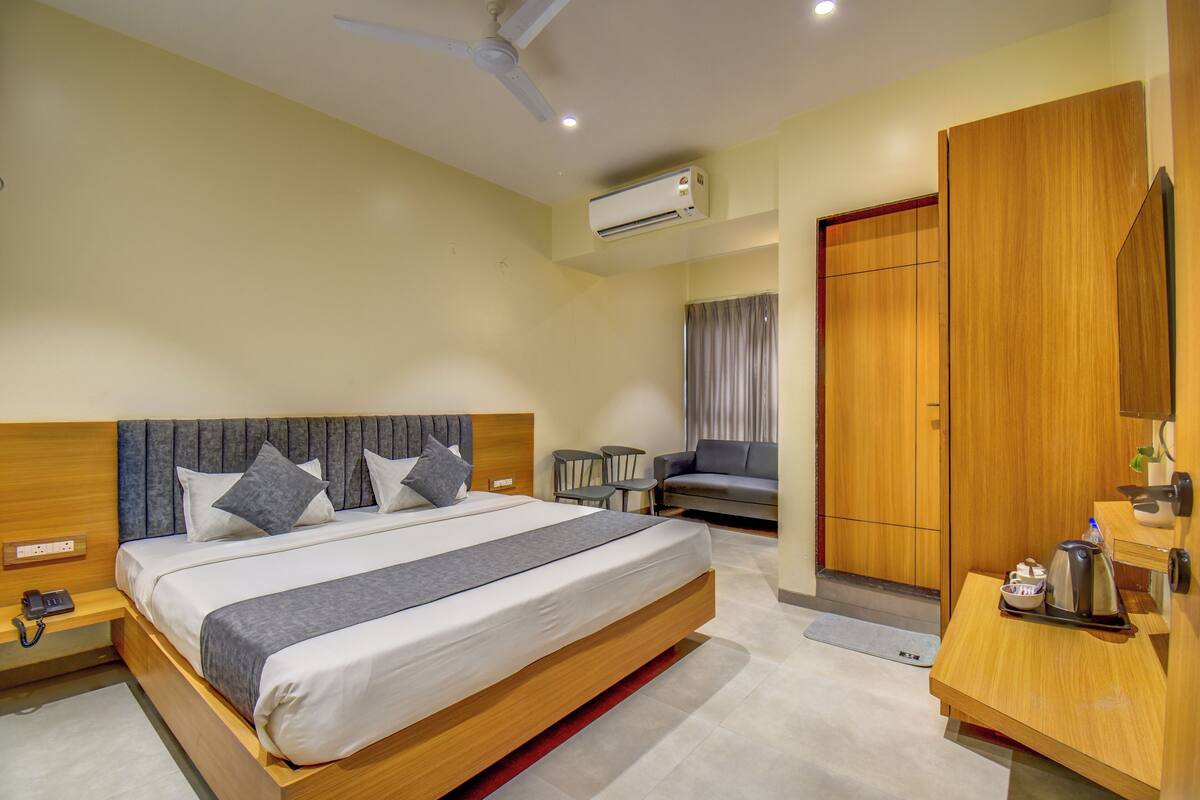 Quarto de hotel moderno com uma cama grande, mesas de cabeceira, uma escrivaninha e um guarda-roupa.