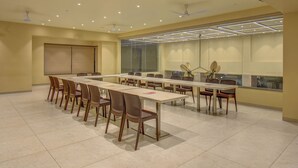 A conference room with a long table, chairs, ceiling fans, and a large window with blinds. - VITS Select Nashik (Nashik)