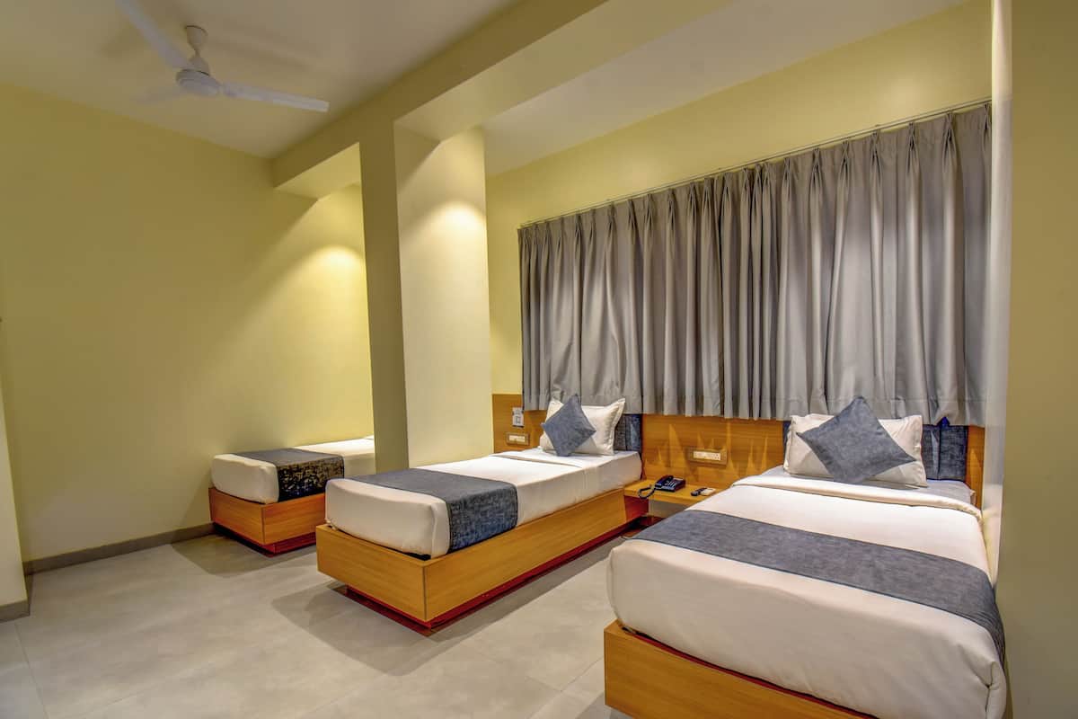 Quarto de hotel com duas camas, um ventilador de teto, um telefone e uma mesinha de cabeceira.