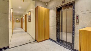 A hotel corridor with a marble floor, wooden wardrobe, and an elevator with a marble surround. - VITS Select Nashik (Nashik)