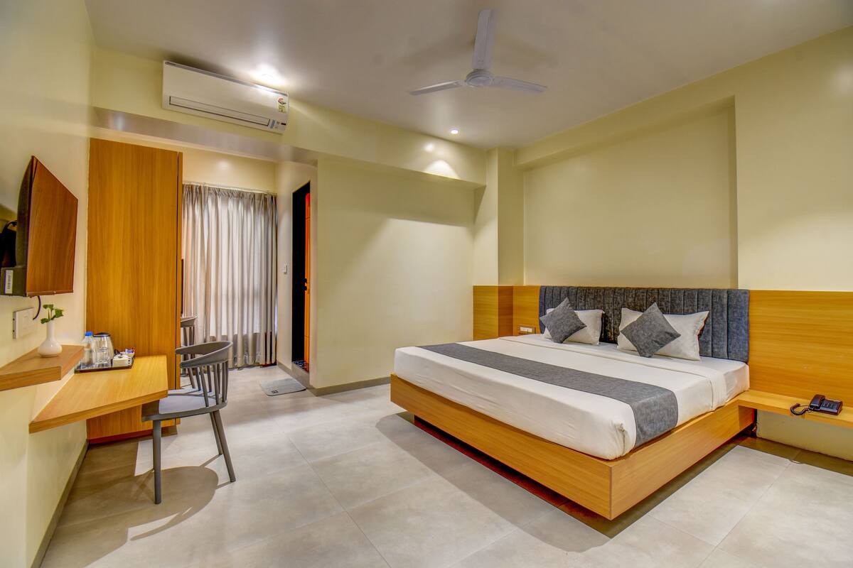 Quarto de hotel moderno com uma cama grande, uma mesa e uma cadeira.