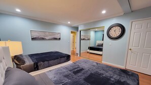 A bedroom with two beds, a mirror, a clock, and artwork on the wall.