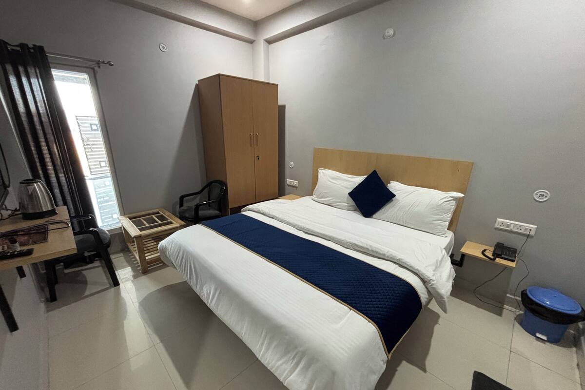 A hotel room with a bed, a desk, a wardrobe, and a small table.