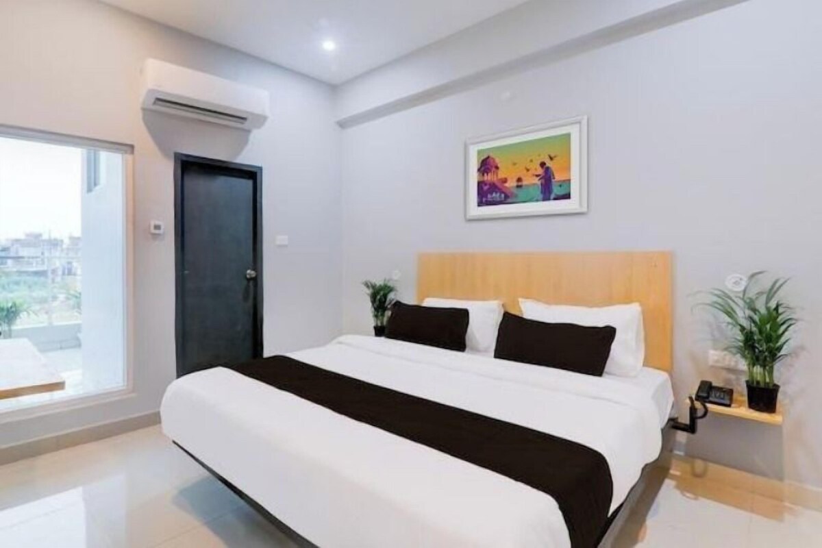 Une chambre d’hôtel moderne avec un grand lit, un tableau au mur et une vue par la fenêtre.