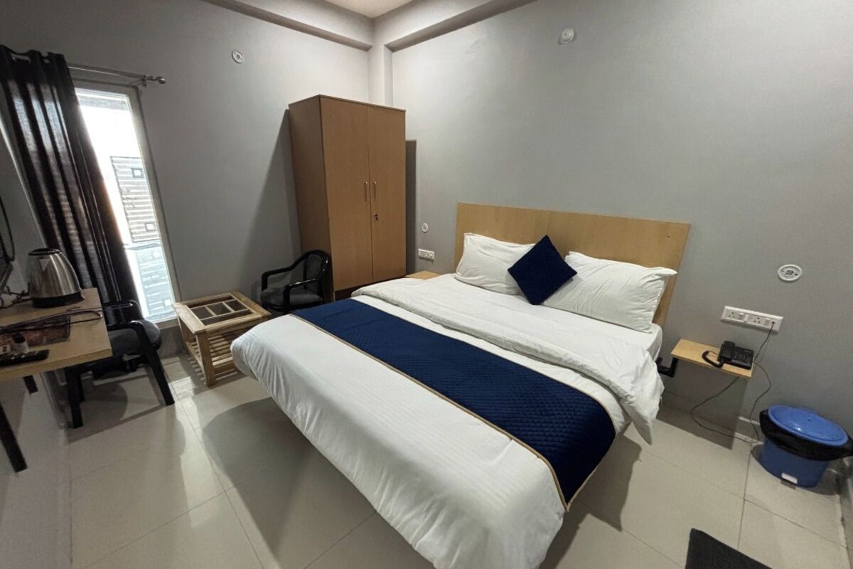 Ein Hotelzimmer mit einem großen Bett, einem Schreibtisch mit Stuhl, einem Kleiderschrank und einem kleinen Tisch mit Telefon.