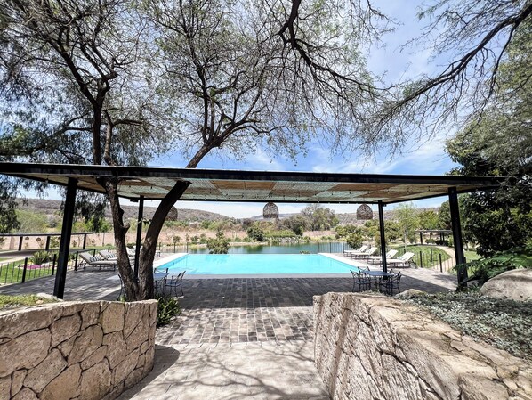 A pool area with a pergola, stone walls, and lounge chairs. - Hotel Boutique Los Remedios (Comonfort)