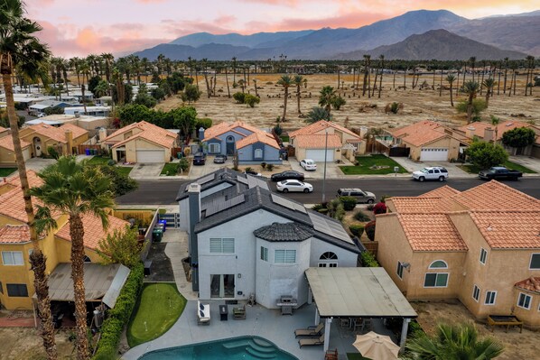 A residential area with houses, a swimming pool, and a mountain in the background.