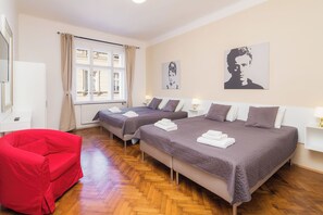Ein Hotelzimmer mit zwei Betten, einem roten Sessel und Kunstwerken an den Wänden.