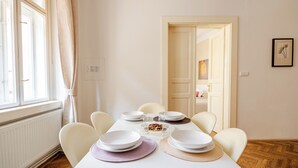 A dining area with a table set for four, white chairs, a white tablecloth, and a framed picture on the wall. - Vincanto Apartments Oldtown Prague 1 (Prague)