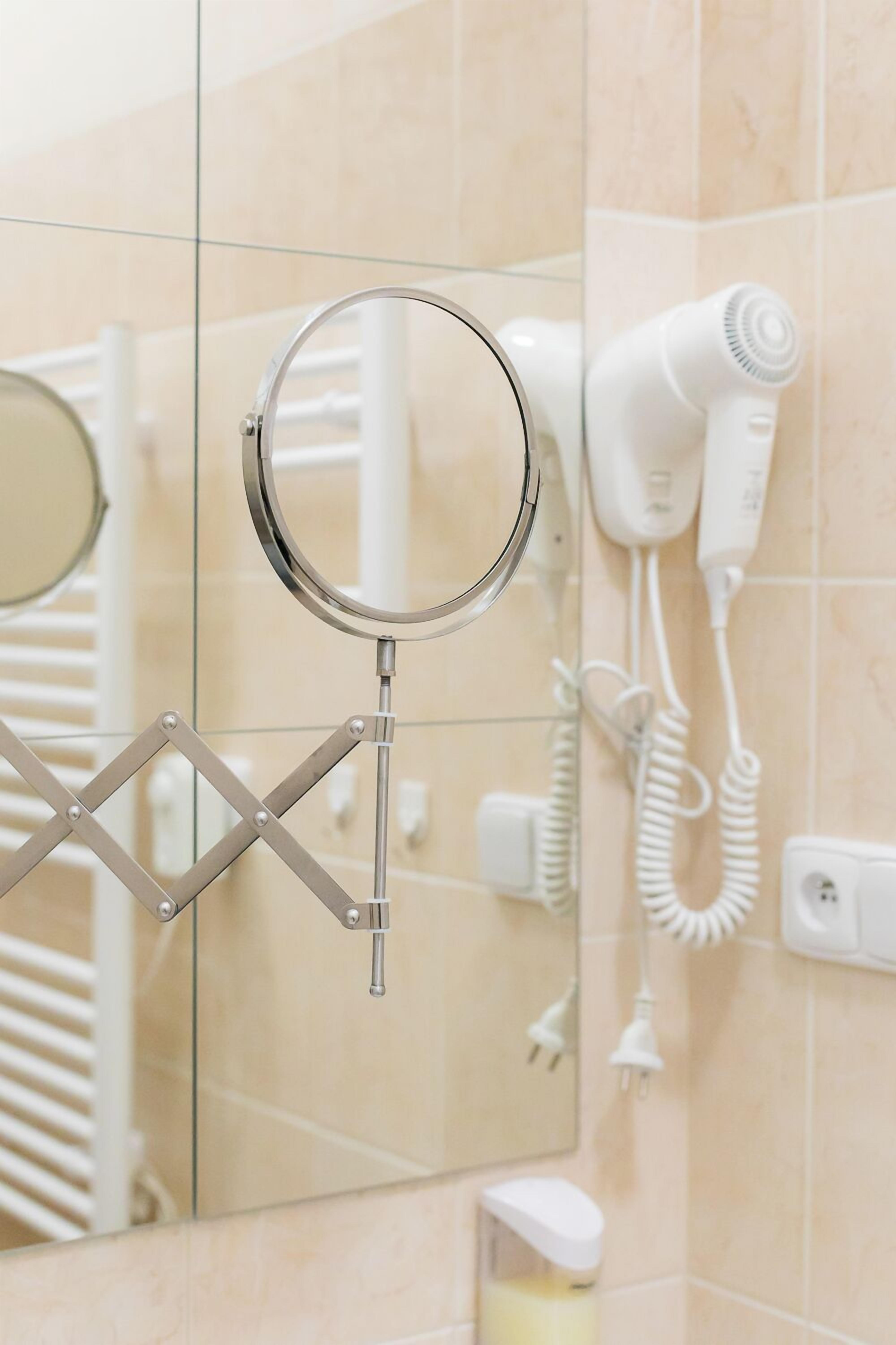 A bathroom with a mirror, a hairdryer, and a towel rack.