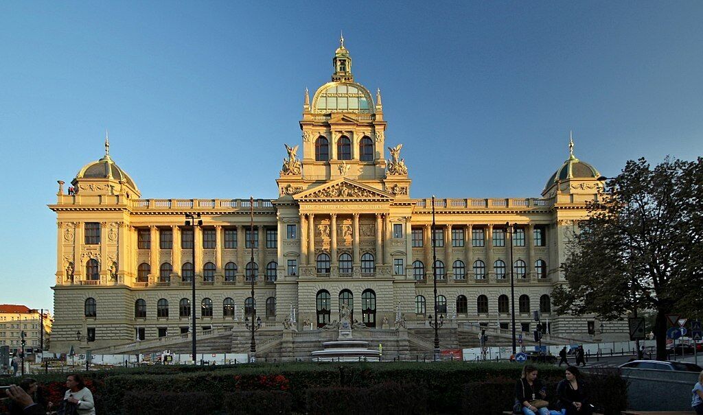 Un grand bâtiment historique doté d’un dôme central et de deux ailes symétriques, caractérisé par une architecture classique et une entrée monumentale.