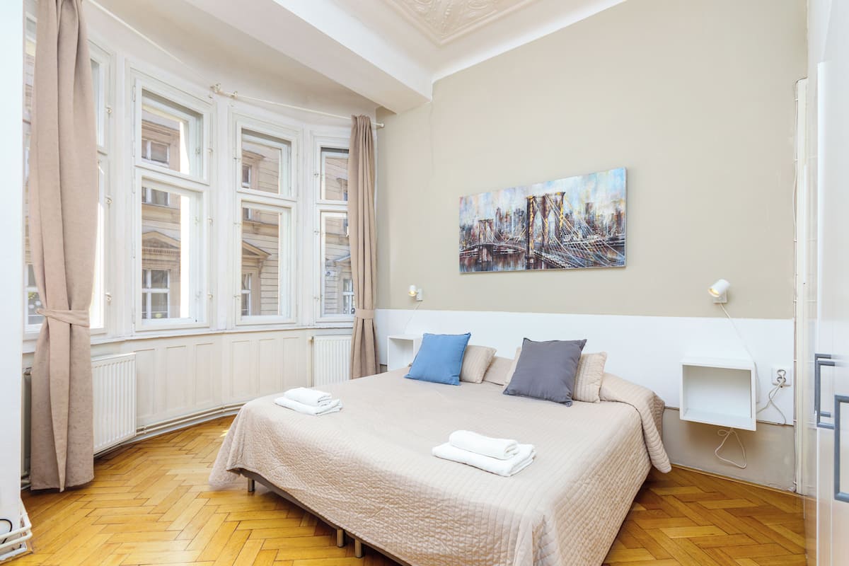 Una habitació d'hotel amb un llit gran, un quadre a la paret i una finestra amb cortines.