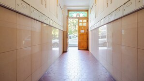 A hallway with tiled walls and a hexagonal patterned floor, leading to a wooden door with a stained glass window. - Vincanto Apartments Oldtown Prague 1 (Prague)