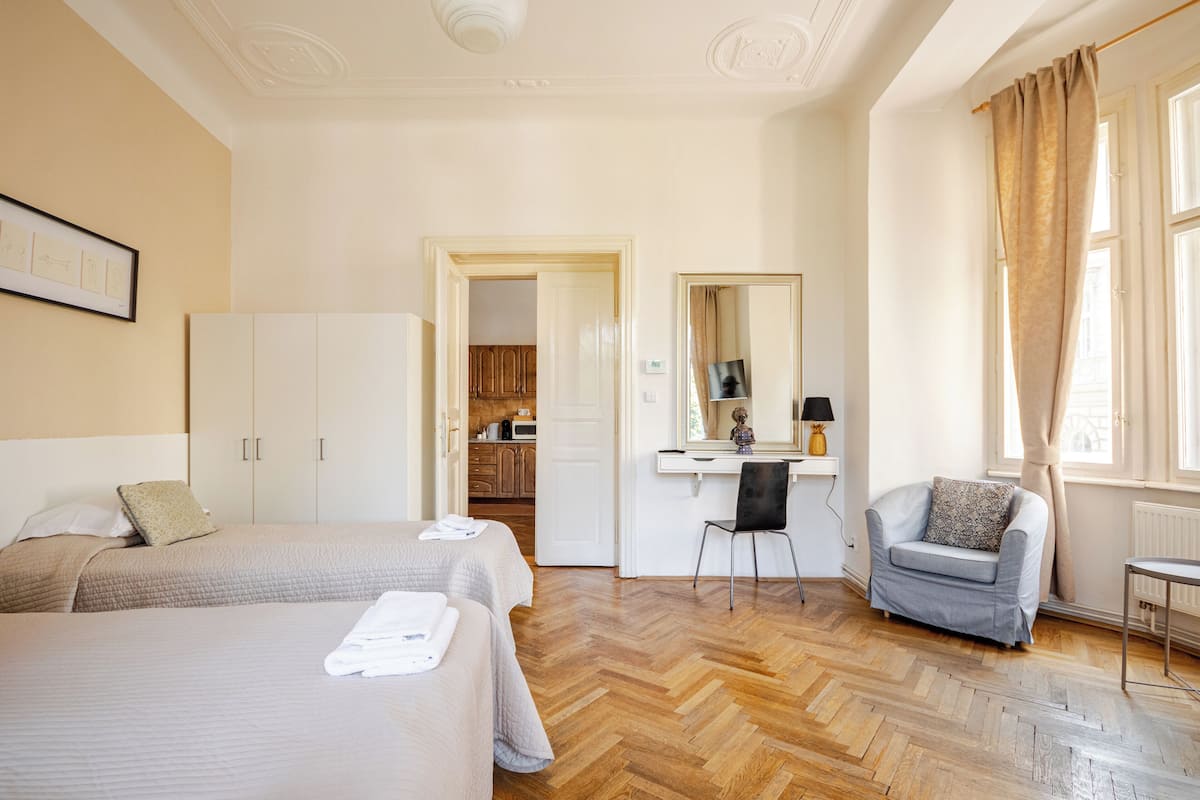 Habitació d'hotel amb dos llits, un escriptori, una cadira i una finestra amb cortines.