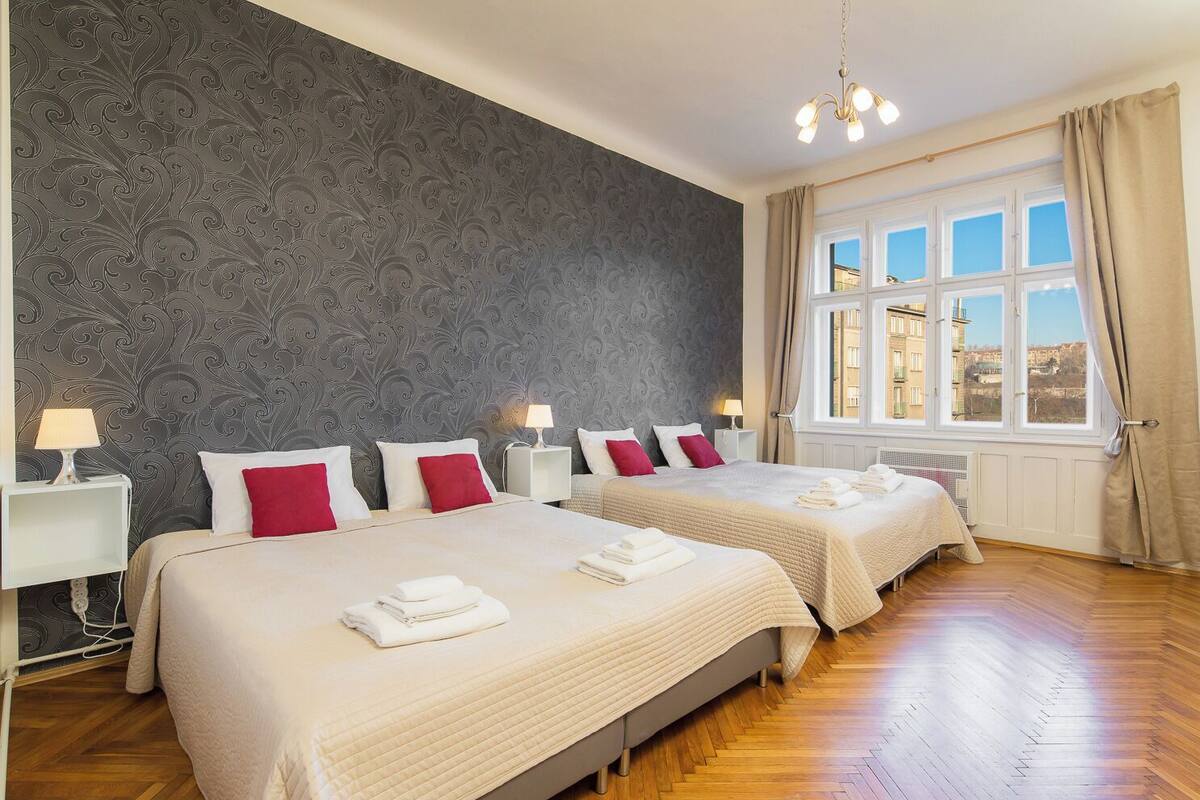 Habitació d'hotel amb dos llits, paper tapet amb un disseny, una finestra gran amb vistes i un penjador.