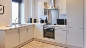 A modern kitchen with white cabinets, a stainless steel range hood, a built-in oven, and a sink. - Host Stay Mariposa Waterloo (Liverpool)