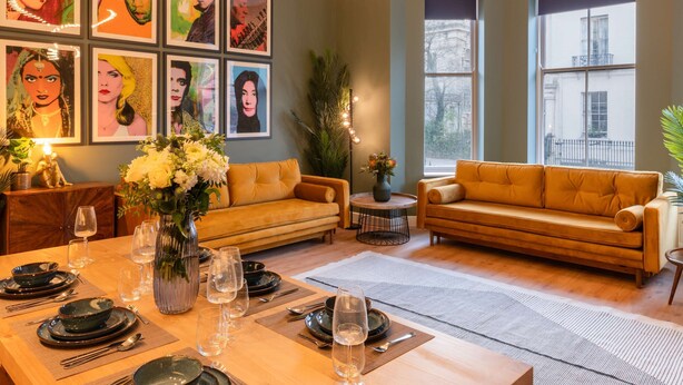 Ein modernes Wohnzimmer mit zwei Sofas, einem Esstisch für sechs Personen und Kunstwerken an den Wänden.