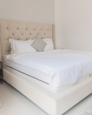 Restful retreat with a large bed and tufted headboard, dressed in crisp white linens.