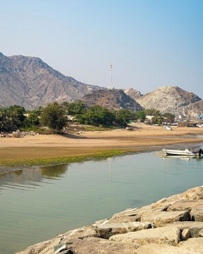 Enjoy a serene riverside retreat with a calm river, anchored boat, and lush vegetation.