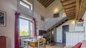 A spacious living area with a dining table, chairs, a sofa, and a staircase leading to an upper level.