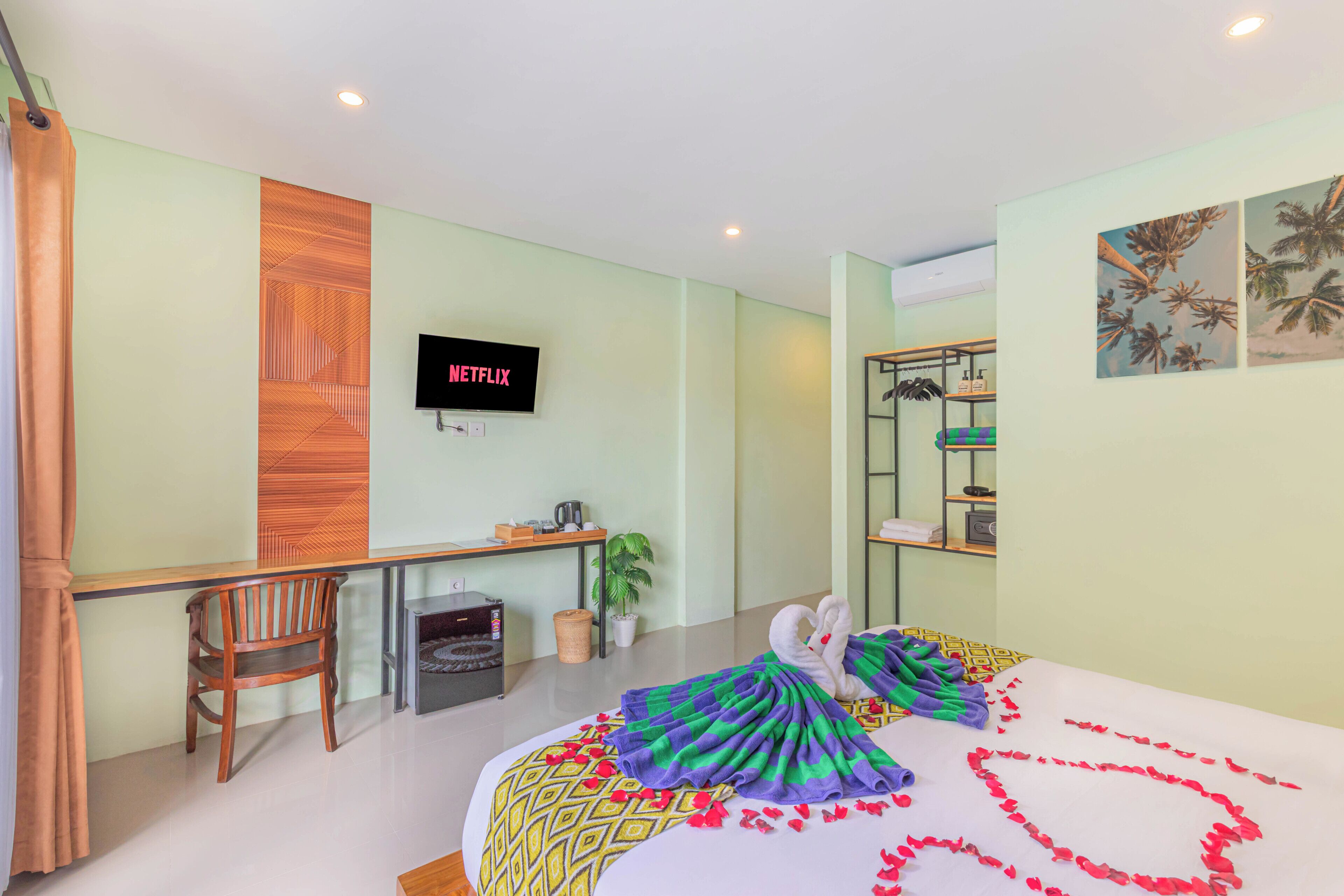 Une chambre d’hôtel équipée d’un lit, d’un bureau, d’une chaise, d’une télévision et d’une étagère fixée au mur.