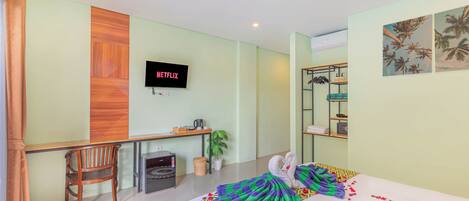 Une chambre d’hôtel équipée d’un lit, d’un bureau, d’une chaise, d’une télévision et d’une étagère fixée au mur.