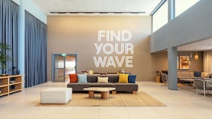 Un hall d’entrée spacieux, avec un grand mur sur lequel est inscrit le texte : « TROUVEZ VOTRE VAGUE ».