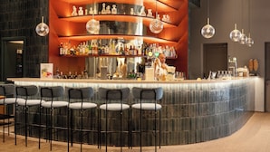 Un espace bar doté d’un comptoir incurvé, de plusieurs étagères remplies de bouteilles et de tabourets de bar.