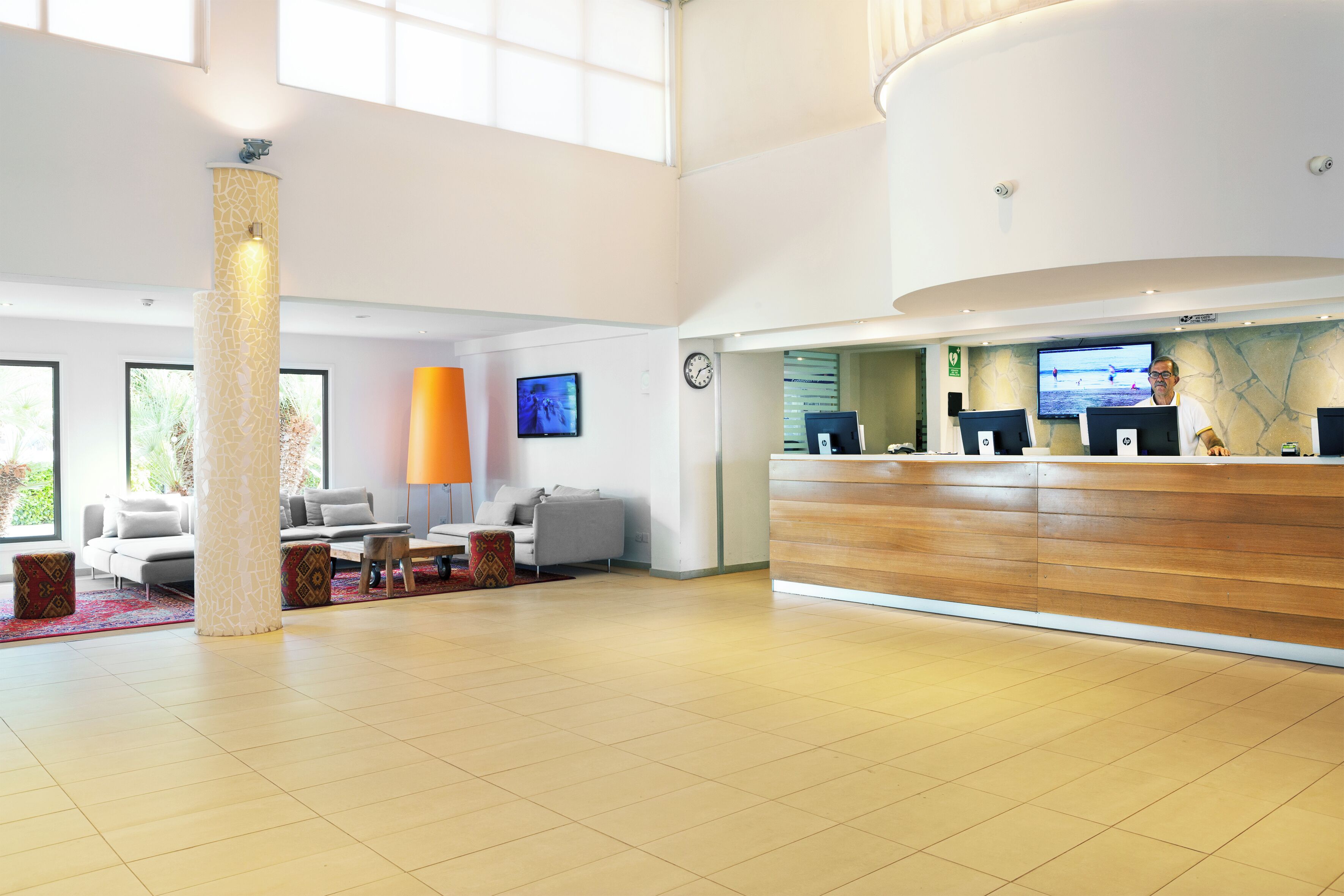 A spacious lobby with a reception desk, seating area, and large windows.