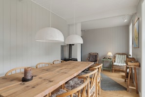 A wooden dining table with chairs, pendant lights, a rug, wicker furniture, and a map on the wall.