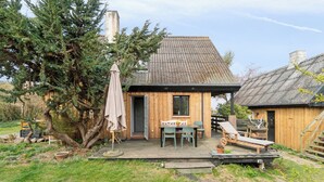 Eine Holzhütte mit einer Terrasse, einem Tisch mit Stühlen und einer Liege.