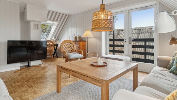 Ein modernes Wohnzimmer mit Fernseher, Holzmöbeln, einem Esstisch und einem großen Fenster mit Blick.