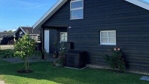 Ein modernes Haus mit geneigtem Dach, einer kleinen Veranda und einem gepflegten Rasen.
