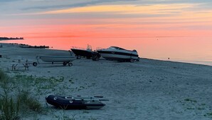 Ein Strand mit Booten und einem Wohnwagen im Sand.