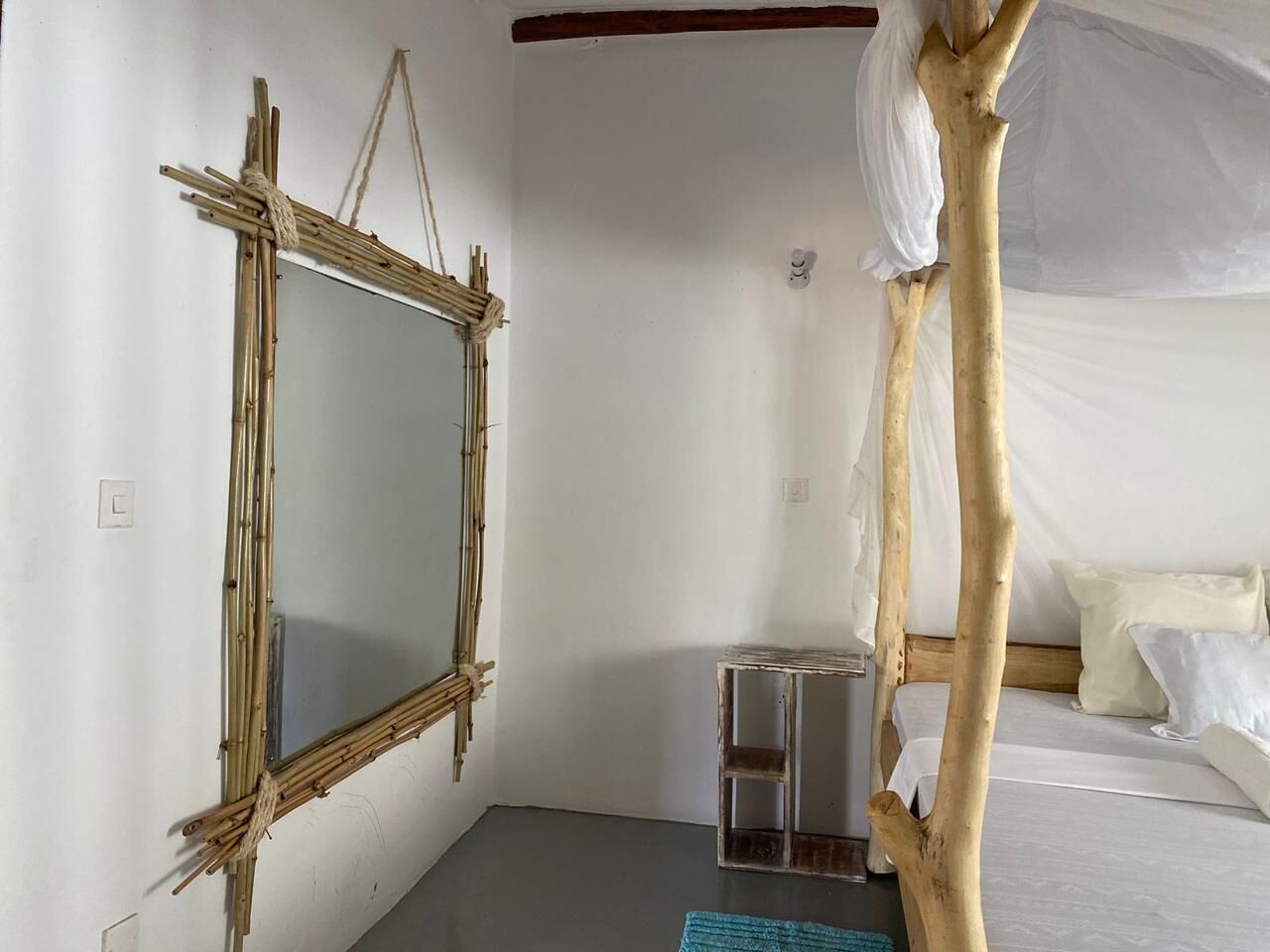 Una stanza con un letto, un tavolino e uno specchio.