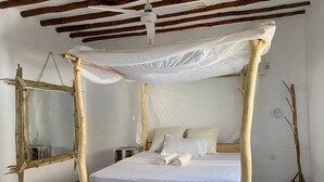 A room with a bed under a canopy, a wooden-framed mirror, and a standing lamp. - MUMBI VILLA WATAMU (Watamu)